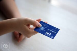 Mão segurando cartão CPF azul com dados visíveis, para consulta RPV TRF5