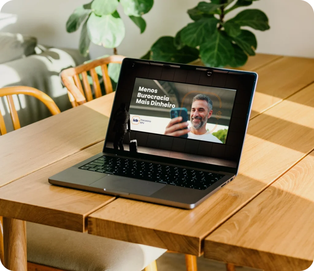 Laptop na mesa de madeira exibindo vídeo sobre menos burocracia e mais dinheiro.